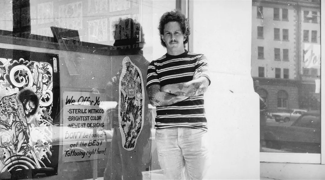 Don Ed Hardy in front of his SD shop on Columbia St, just off of Broadway. The reflection in the first photo is the Army-Navy YMCA building.