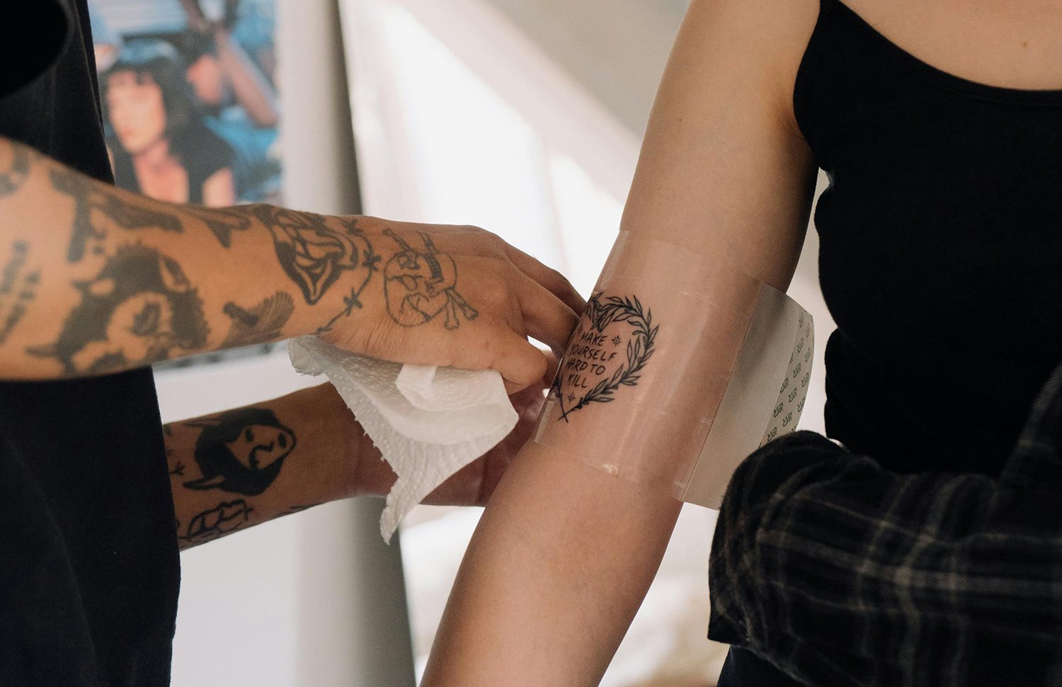 Tattoo artist carefully covers a fresh tattoo with a second skin (adhesive film), Cottonbro Studio